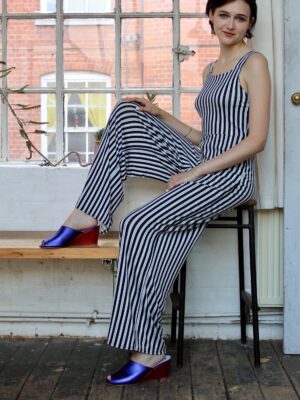 Marla in Ops&Ops No15 Metallic Purple wedge mules worn with striped, strappy jumpsuit