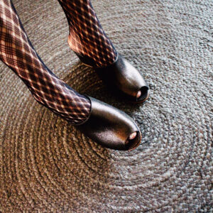 Ops&Ops No15 Black Granite wedge mules worn with patterned tights on braided rug