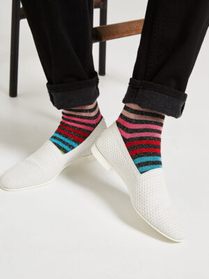 Ops&Ops No10 Action White leather flats close-up worn with multi-striped lurex socks and black turned-up jeans