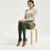 Marla sitting in Ops&Ops No17 Mushroom flats with bottle green tights, short putty-coloured vinyl skirt and grey sweater looking straight to camera