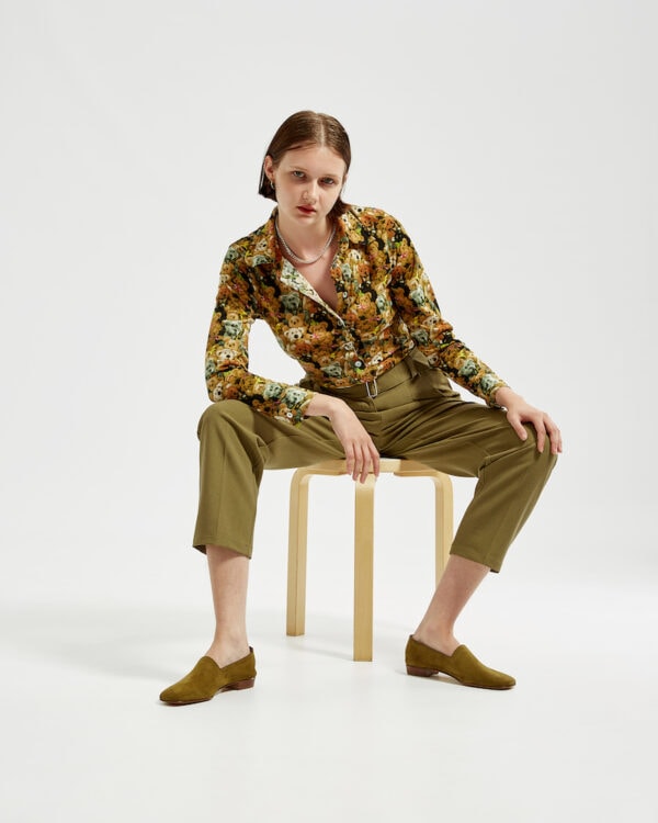 Marla sitting in Ops&Ops No17 Olive nubuck flats with olive-coloured pleated trousers and vintage Warehouse teddy bear patterned shirt