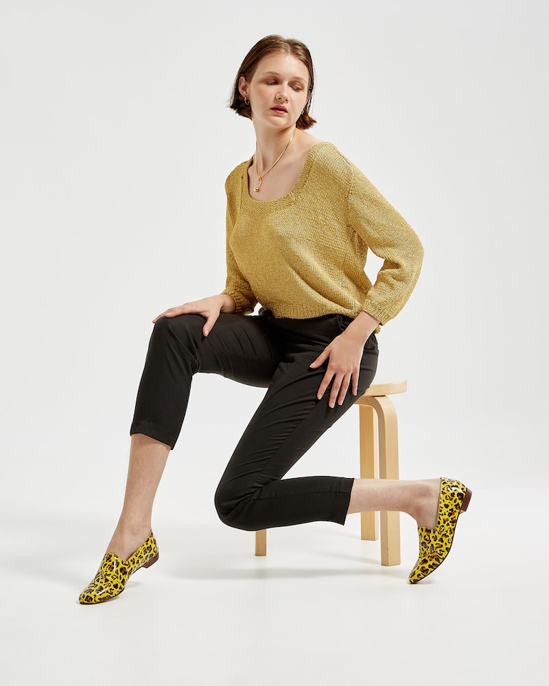 Marla in Ops&Ops No10 Leopard print patent flats with gold knitted sweater and black cropped trousers sitting on stool