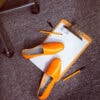 Ops&Ops No10 Turmeric leather flats shot with clipboard, pens and office chair. Photo: Lydia White