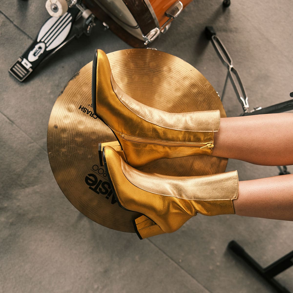 Hannah Hu wearing Ops&Ops No17 Gold Duo boots, resting feet on a drum symbol