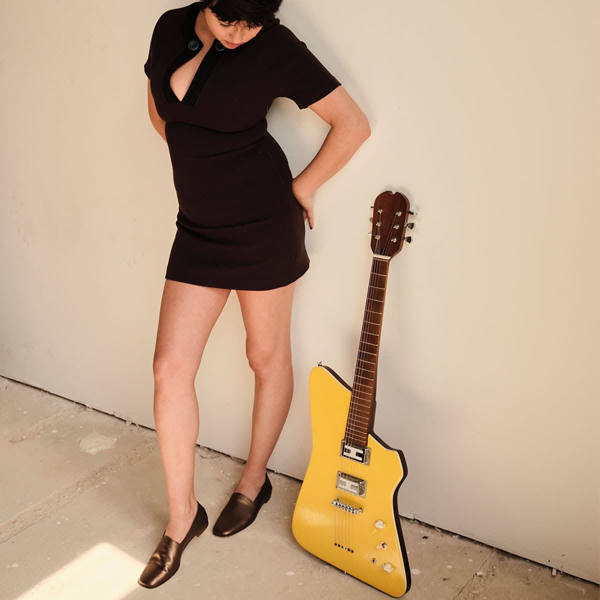 Hannah Hu wearing Ops&Ops No17 Bronze flats standing next to a guitar